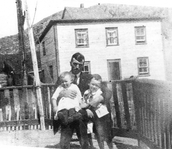 205: J V McCarthy with his children Mollie and Vince, sitting on Dunphy's porch. Bill Webber's  house in the background. (circa 1923)